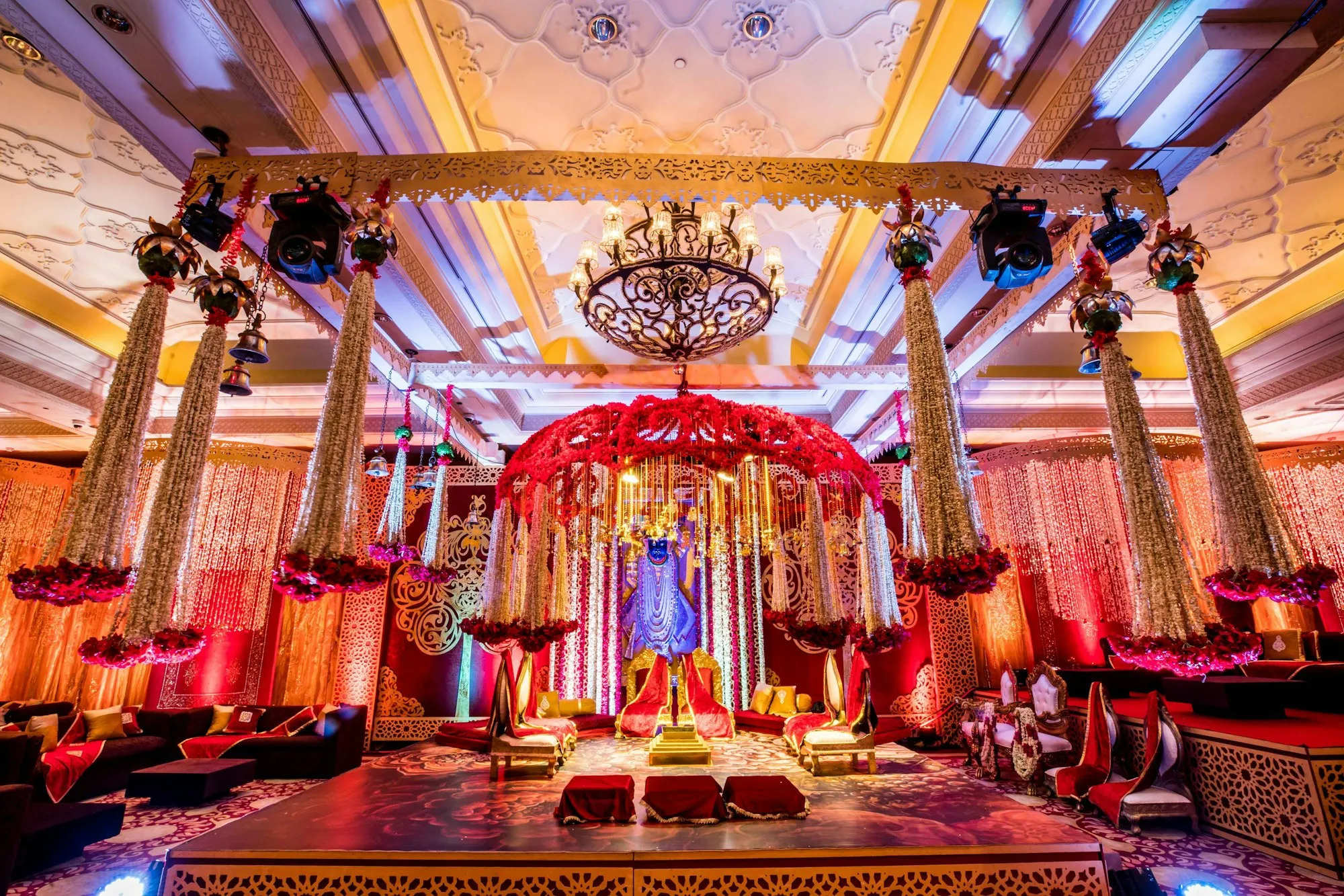 A red and gold wedding stage beneath a chandelier